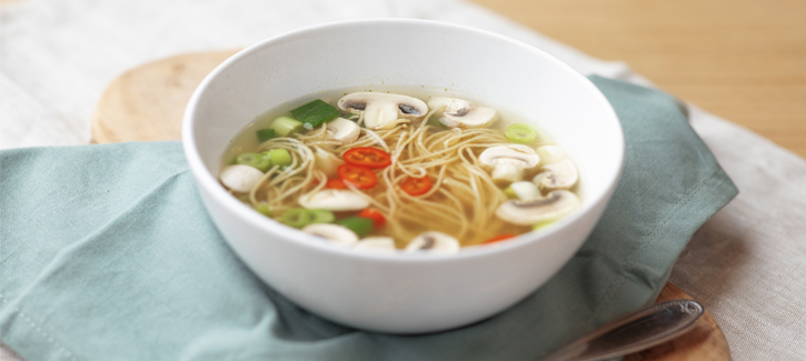 Heldere groentesoep met champignons en lente-ui